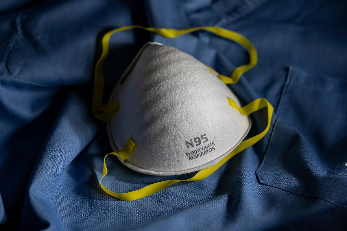 A white N-95 respirator mask placed on a blue shirt, indicating safety measures against mold exposure.